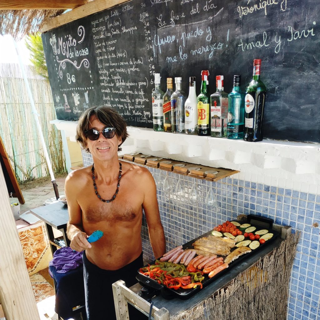 Mann an der Bar, der eine Plancha mit Gemüse und Fleisch zubereitet.