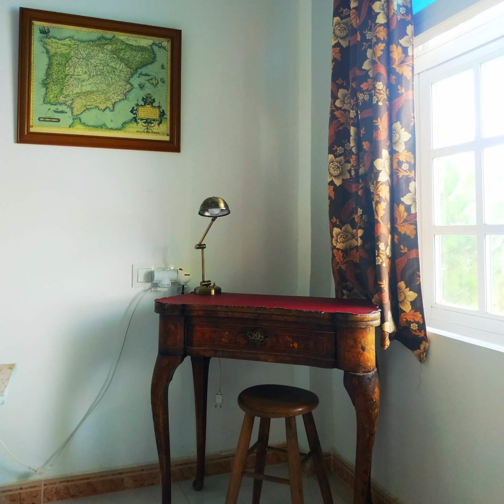bureau avec une lampe ancienne, tabouret et ancienne carte de l'Espagne encadrée au mur