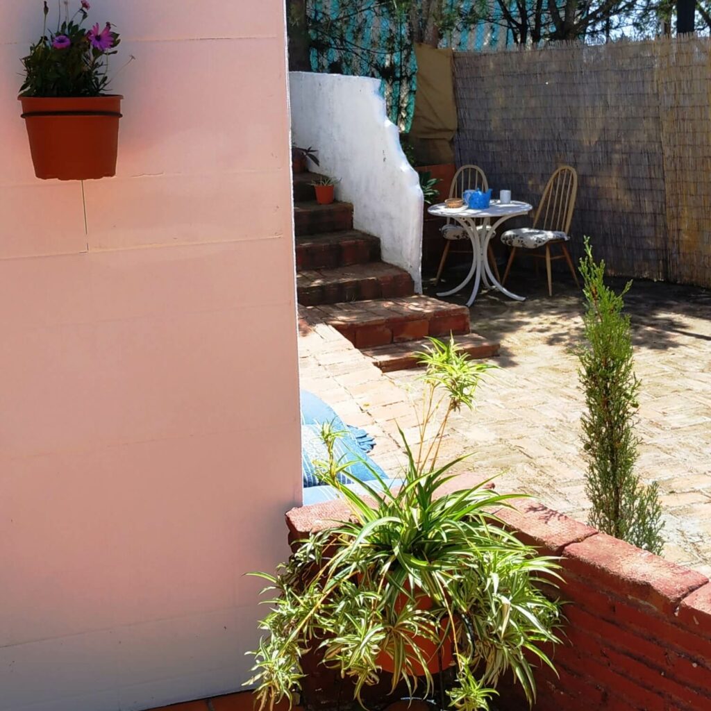 Terrasse eines weißen andalusischen Hauses von hinter einer weißen Mauer aus gesehen.