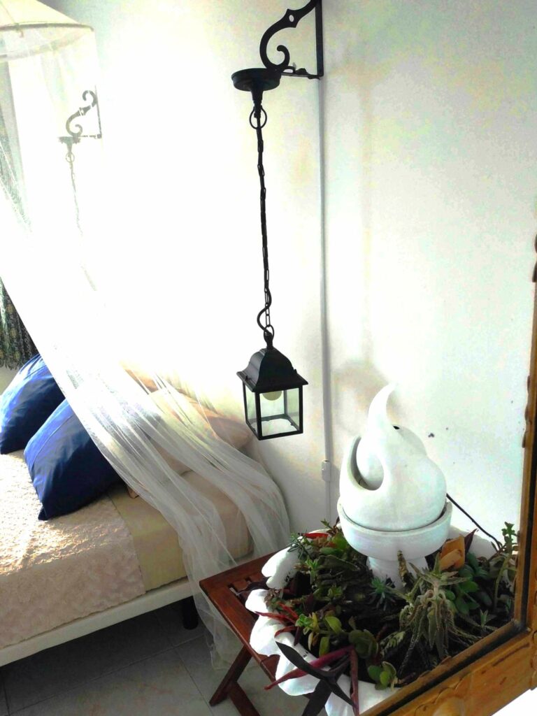 grote spiegel die een bed en een pot bloemen weerspiegelt