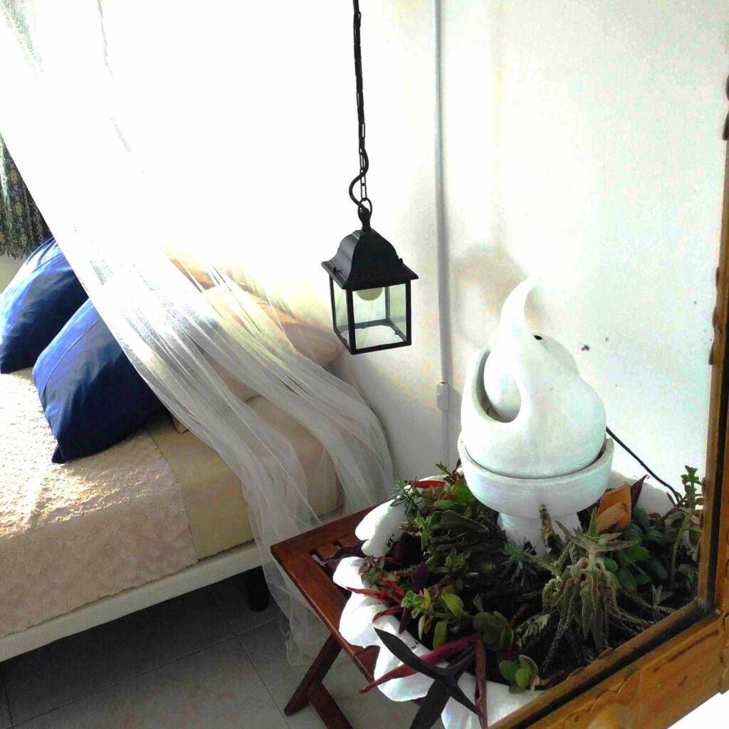 grand miroir dans lequel se reflète un lit et un pot de fleurs