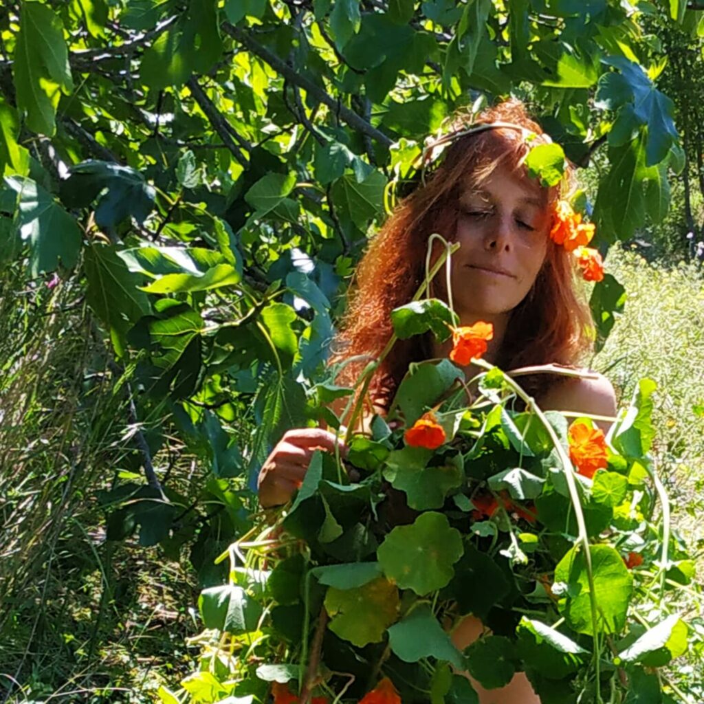 Femme marchant dans la nature, les bras chargés d'une grande brassée de capucines