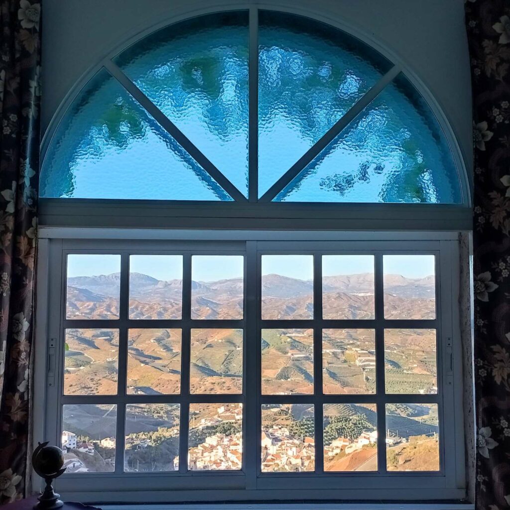 Gesloten raam waardoor je de Andalusische bergen kunt zien