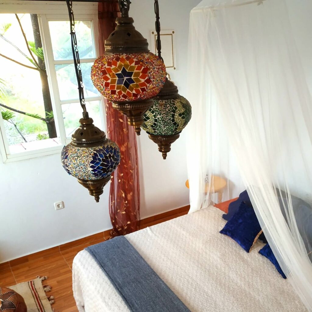 Schöne bunte Deckenleuchte im arabischen Stil, mit perspektivischem Blick auf ein Bett und ein Moskitonetz