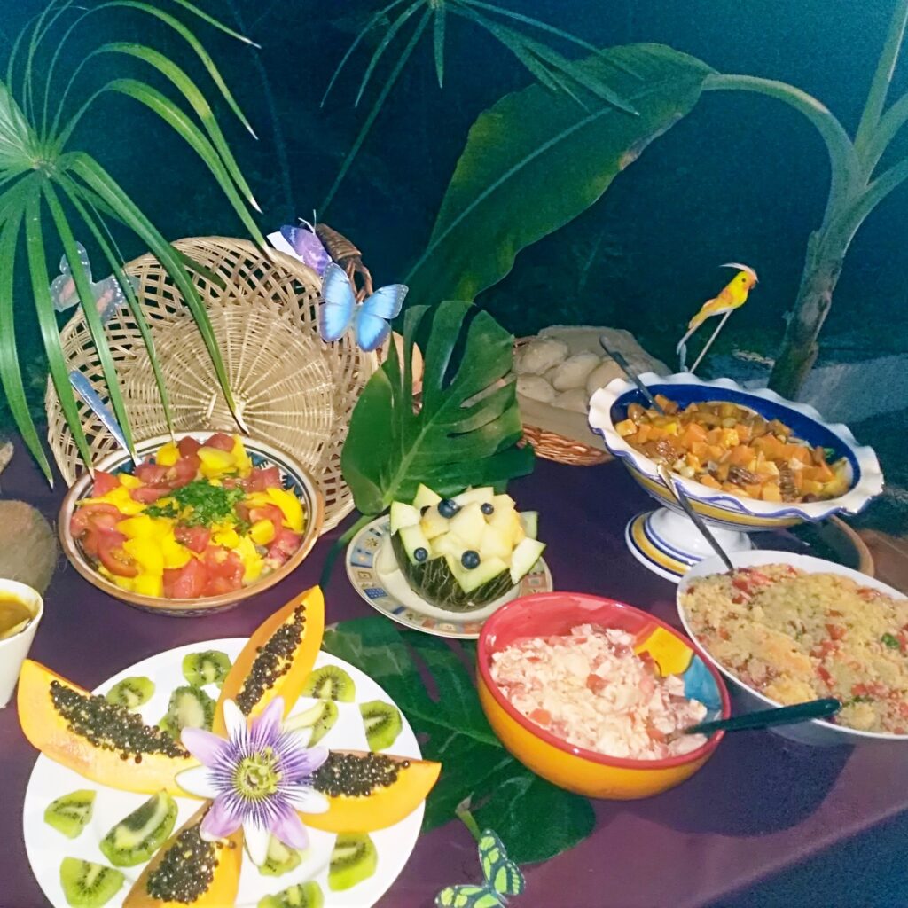 un buffet de salades et de fruits très colorés, décorés de fleurs, feuillages, oiseaux et papillons.