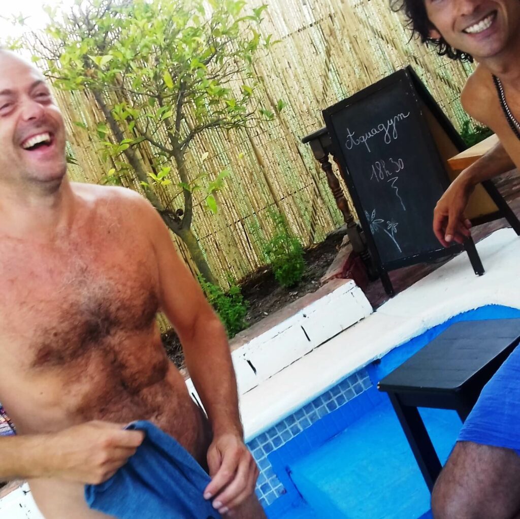 Poorly framed photo of two men laughing on a pool terrace