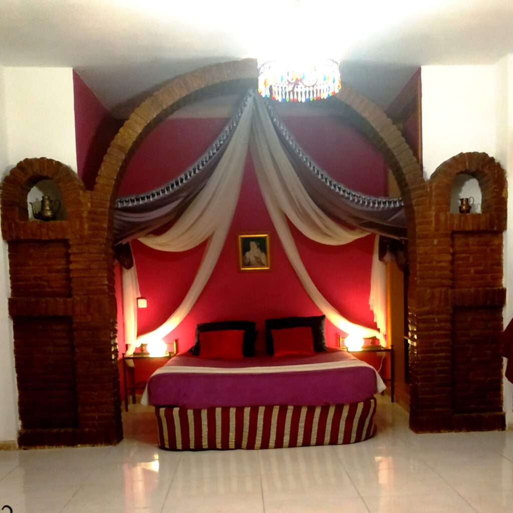 Bett in einem Alkoven mit Vorhängen, der von mehreren Lampen beleuchtet wird